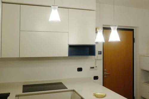 a kitchen with white cabinets and lights above a counter at Orea Spiti - Modern Oasis Near Milan in Assago