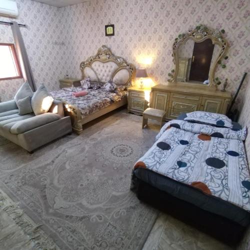 1 dormitorio con cama, sofá y espejo en العين الهيلي مصباح بيت 11, en Al Ain