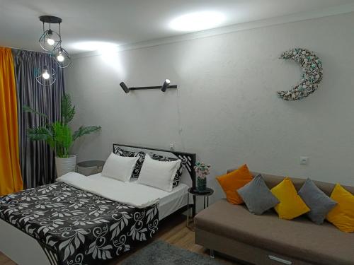 1 dormitorio con 1 cama y 1 sofá en Островок Уюта, en Aktobe