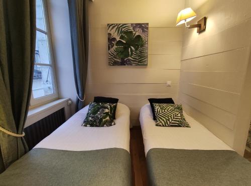 two beds in a small room with a window at Le Pavillon Saint-Martin in Souillac