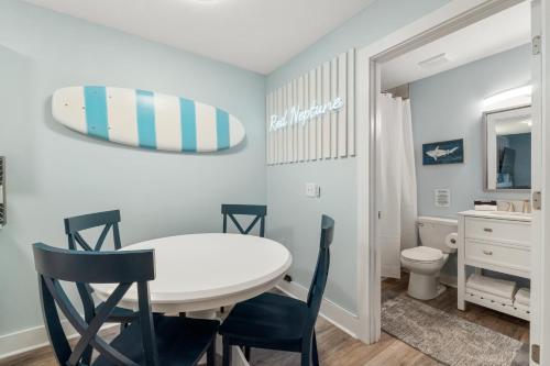 a dining room with a table and chairs and a surfboard on the wall at Red Neptune by Nautical Properties in Panama City Beach