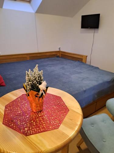 a table with a vase of flowers on top of a bed at Izba Vladimír Penzión pod Smrekom in Martin