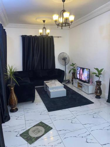 a living room with a black couch and a tv at Charly-chic@ in Cotonou