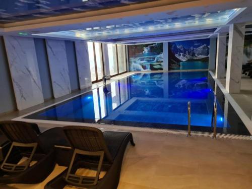 an indoor swimming pool in a building with chairs at President Kop A4 in Kopaonik