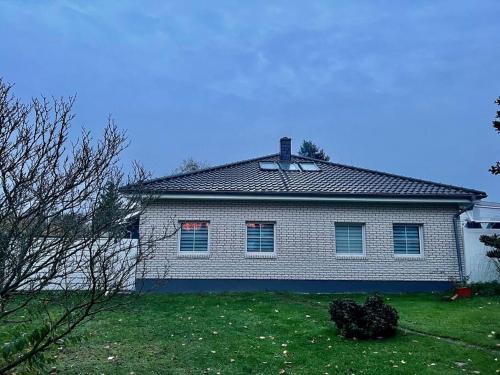 a white house with a roof on a yard at Schönes 2 Zimmer Apartment an der Stadt Grenze mit Klimaanlage in Blankenfelde