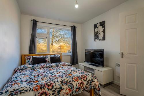 a bedroom with a bed and a tv and a window at Abdon house in Birmingham