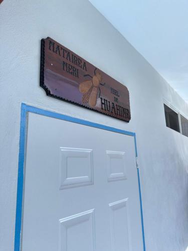 a sign above a white door with a chicken on it at Meri Lodge Huahine XXThe Bee HouseXX in Fare