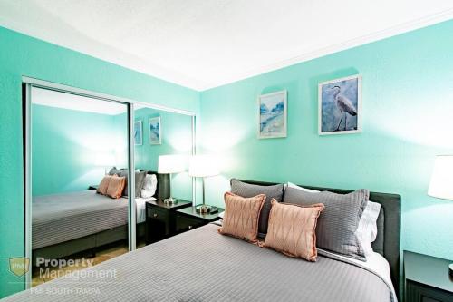 a bedroom with blue walls and a bed with a mirror at Cool Notes - Enjoy the sounds of the Bay in Tampa