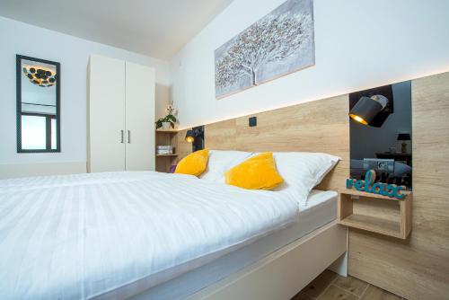 a bedroom with a large white bed with yellow pillows at Apartment & rooms Vila Toplissa in Varaždinske Toplice