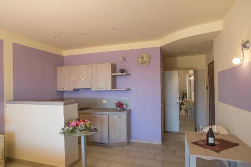 a kitchen with purple walls and a table and a refrigerator at Residence Usignolo in Trarego