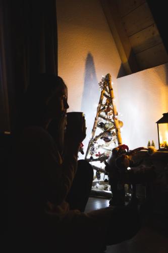 a woman holding a cup of coffee in front of a christmas tree at Natures Escape Kozarica in Šavnik