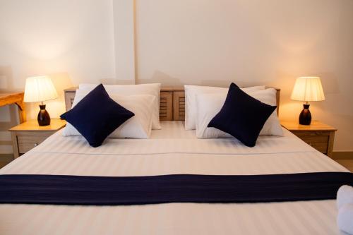 a bedroom with a large bed with blue and white pillows at Biosphere Inn in Dharavandhoo