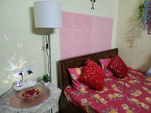 a bed with red pillows and a table with a lamp at Bhumi Holiday Home in Alibaug