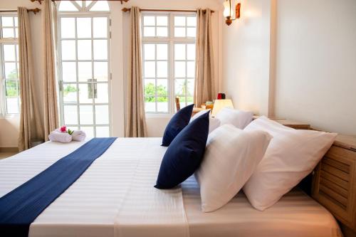a bedroom with a bed with blue and white pillows at Biosphere Inn in Dharavandhoo