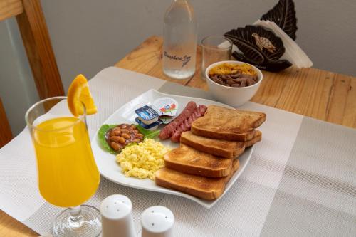 a plate of breakfast food on a table with orange juice at Biosphere Inn in Dharavandhoo