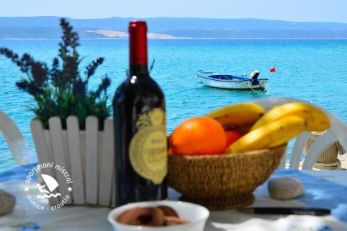a bottle of wine and a bowl of fruit on a table at Apartments Mistral in Mimice