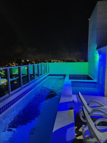 - une piscine avec vue sur la ville la nuit dans l'établissement Porto Blue Makaranduba, à Porto de Galinhas