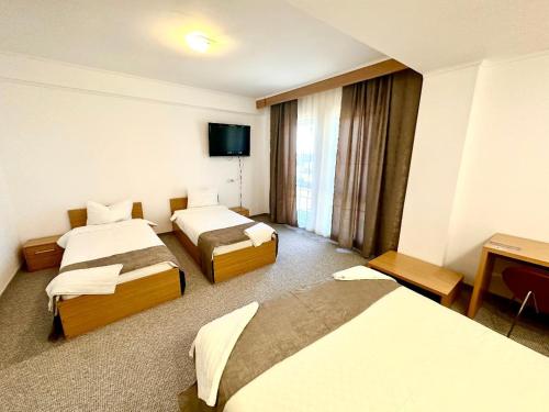 アラドにあるHotel Rigaのベッド3台、薄型テレビが備わるホテルルームです。