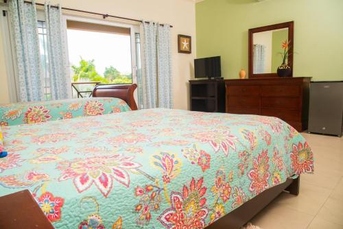 a bedroom with a bed and a dresser and a mirror at MARIBELLA@CRYSTAL COVE OCHO RIOS in Stanmore Grove