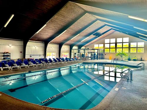 a large swimming pool with blue chairs in a building at Cape Cod Irish Village - The Emerald Resort in Barnstable
