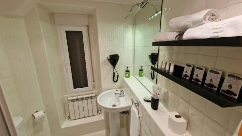 ein weißes Badezimmer mit Waschbecken und Spiegel in der Unterkunft El loft de la catedral VUT-09/547 in Burgos