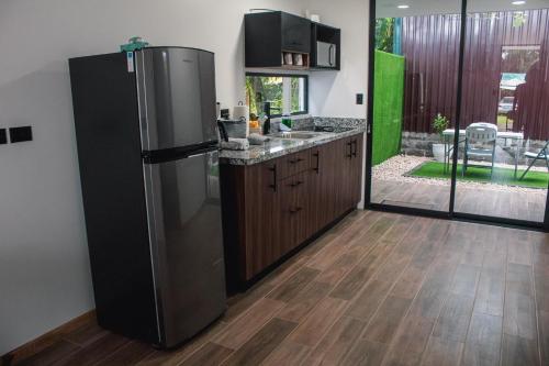 a kitchen with a stainless steel refrigerator and wooden cabinets at Villa El Bosque Dorado in Fortuna