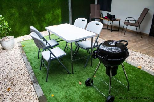a table and chairs with a grill on the grass at Villa El Bosque Dorado in Fortuna