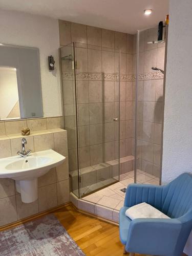 a bathroom with a shower and a sink and a blue chair at Wellness Oase auf dem Land in Buttstädt