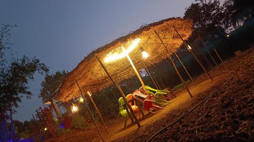 a playground at night with a straw roof at The Royal Ascot Holiday Home in Alibaug