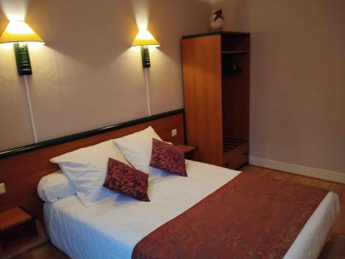 a bedroom with a bed with two pillows on it at Hôtel Moderne in Prades-dʼAubrac