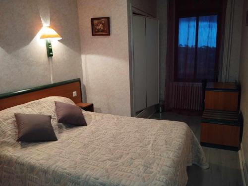 een slaapkamer met een bed met 2 kussens erop bij Hôtel Moderne in Prades-dʼAubrac