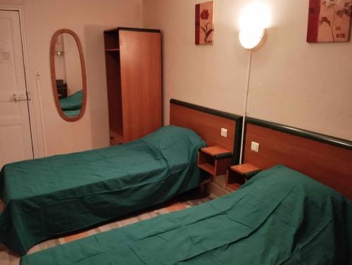 a hospital room with two beds and a mirror at Hôtel Moderne in Prades-dʼAubrac