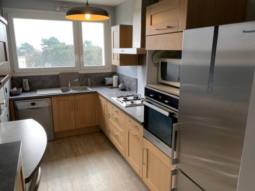 une cuisine avec un réfrigérateur en acier inoxydable et des armoires en bois dans l'établissement Appartement de charme, 76 m2, Quartier St GABRIEL, à Caen