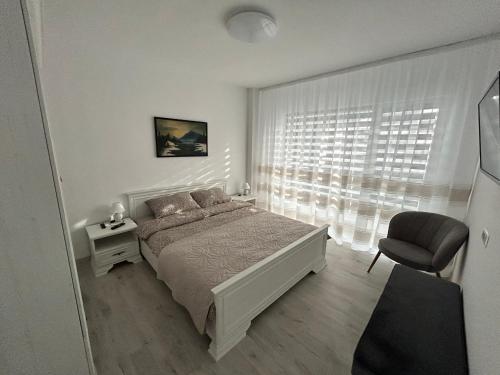 1 dormitorio con 1 cama, 1 silla y 1 ventana en 1 Mai - Luxury Park Apartments - Self Check-in - Private parking - 2 en Craiova