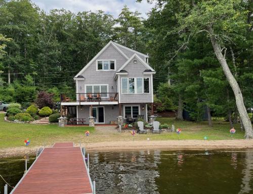 a house on the shore of a lake with a dock at OWL HOUSE LIMIT 8 home in Wakefield