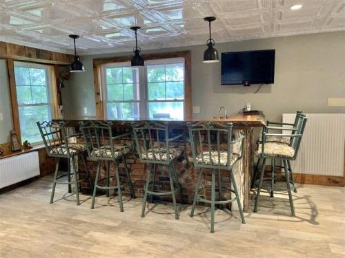 a kitchen with a bar with chairs and a tv at OWL HOUSE LIMIT 8 home in Wakefield