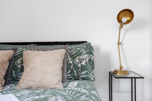 City-Centric Living Cozy 1-Bedroom Apartment في برادفورد: سرير بمخدات خضراء وبيضاء ومصباح