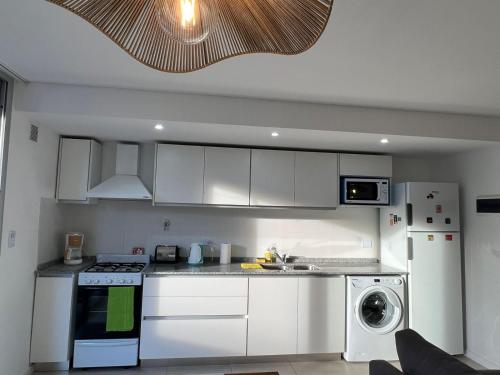 cocina con armarios blancos, lavadora y secadora en Confortable departamento en Castelar - Zona Céntrica. en Castelar