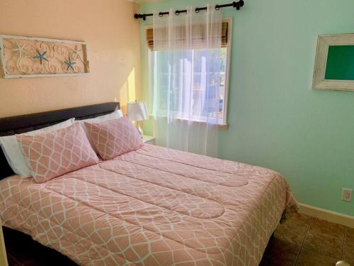 een slaapkamer met een bed met een roze dekbed en een raam bij The Great Escape - Panoramic Sunset views in Tampa