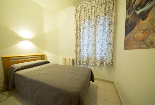 a small bedroom with a bed and a window at Turó de L´Home in Santa María de Palautordera