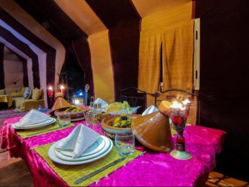 a table with plates of food on a pink table cloth at Merzouga Desert Campsite &Activities in Merzouga