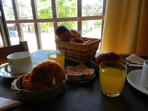 a table topped with baskets of bread and orange juice at Hotel Vireo in Villa Gesell