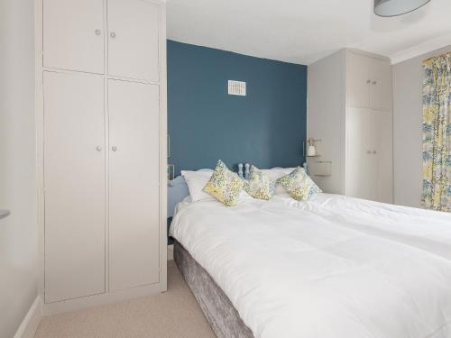 a bedroom with a large white bed with a blue wall at Llywnfor in Morfa Nefyn