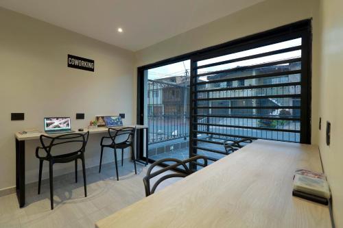 un bureau avec un bureau, des chaises et une grande fenêtre dans l'établissement Casa Indigo Laureles-Estadio con Jacuzzi, à Medellín