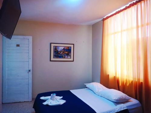 una camera con un letto e una finestra con un asciugamano di Hostal Real Piura - Oficial a Piura