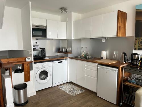 une cuisine avec des armoires blanches et une laveuse et une sécheuse dans l'établissement Refuge des pirates, à Deauville