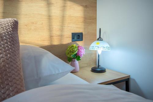 a bed with a lamp and a vase of flowers on a table at Apartment & rooms Vila Toplissa in Varaždinske Toplice