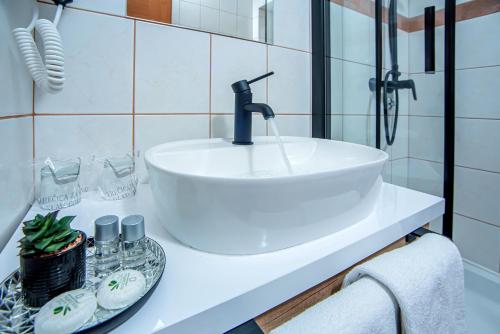 a white sink in a bathroom with white tiles at Apartment & rooms Vila Toplissa in Varaždinske Toplice