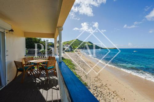 a balcony with a table and chairs on the beach at Très jolie 3 pièces à Gd Case les pieds dans l'eau in Grand Case