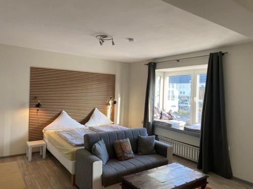 1 dormitorio con cama, sofá y ventana en Budgethotel Stadtbett Wolfsburg, en Wolfsburg